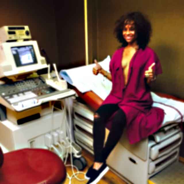 A woman sitting on top of a bed in front of an ultrasound machine.